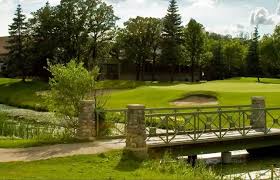 a bridge over a creek at a golf course with the sand hazard in the background